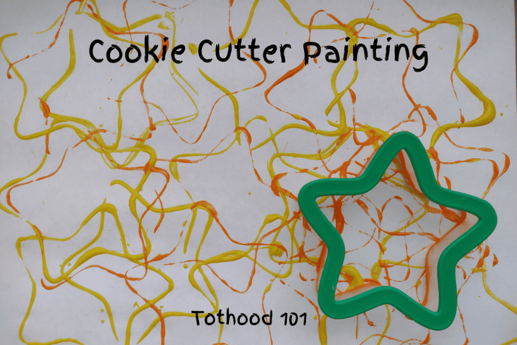 Cookie cutter painting activity done with a star shape dipped in yellow and orange paint. 