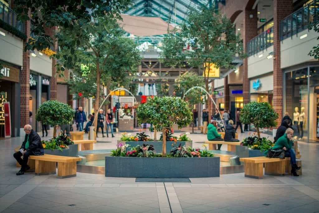 Inside of a mall, benches with people sitting on them.