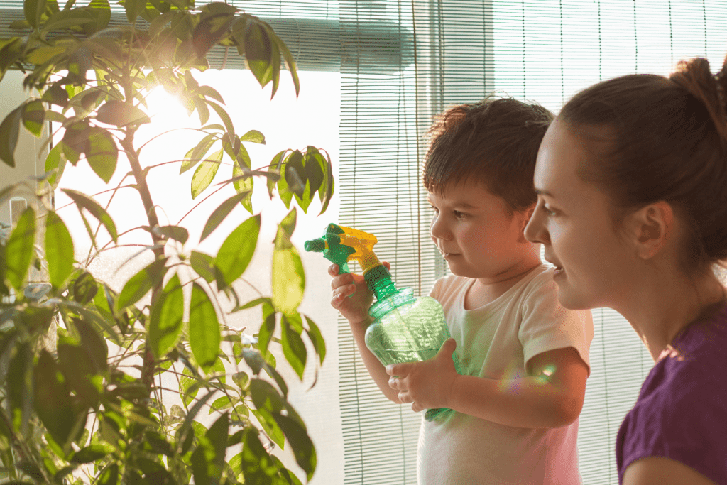 A mom with a preschool boy watering plants with a spraybottle.