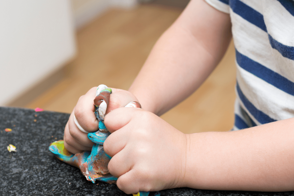 A child's hands squshing playdough.