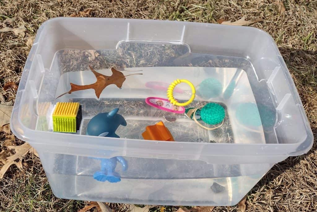 Plastic tub filled with water with items that are sinking or floating