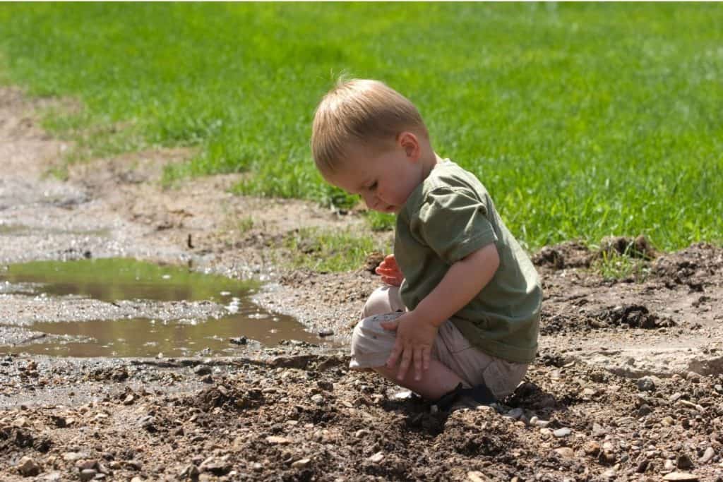 Preschool boy playing in the mud
