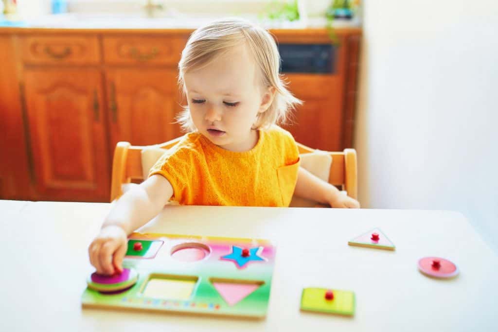a preschool girl doing a shape puzzle