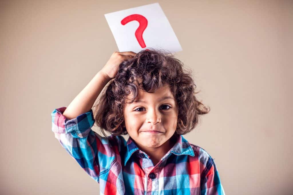 A boy holding a question mark card over his head.