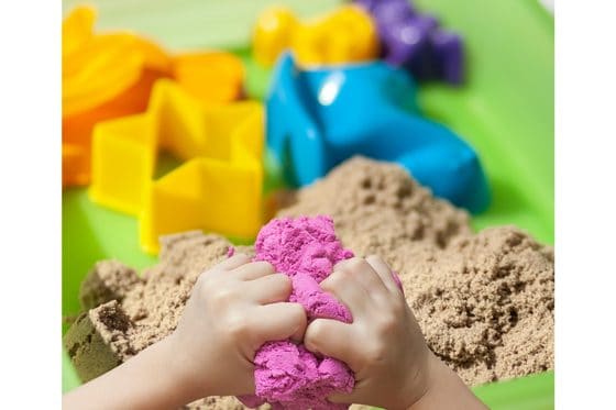 hands playing with kinetic sand