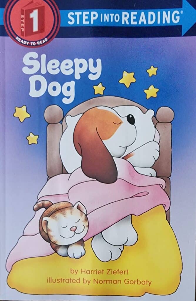 Book cover of Sleepy Dog by Harriet Ziefert. A dog is sleeping on a bed with a cat at his feet.