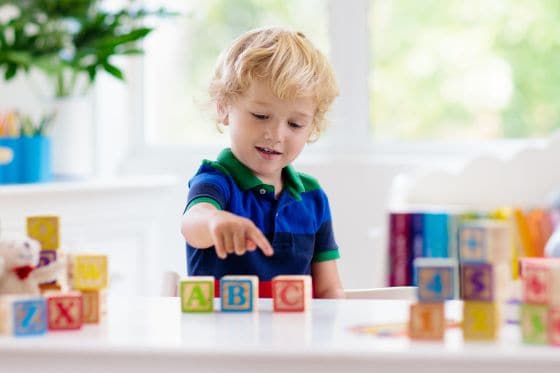 A blond haired boy playing with alphabet blocks